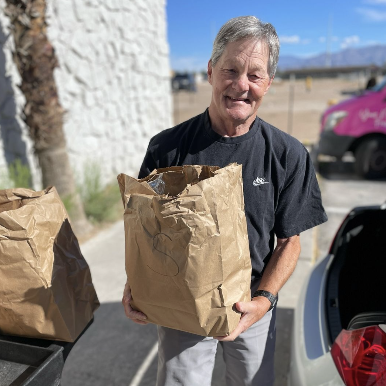 A man holding brown bags of food in his hands.